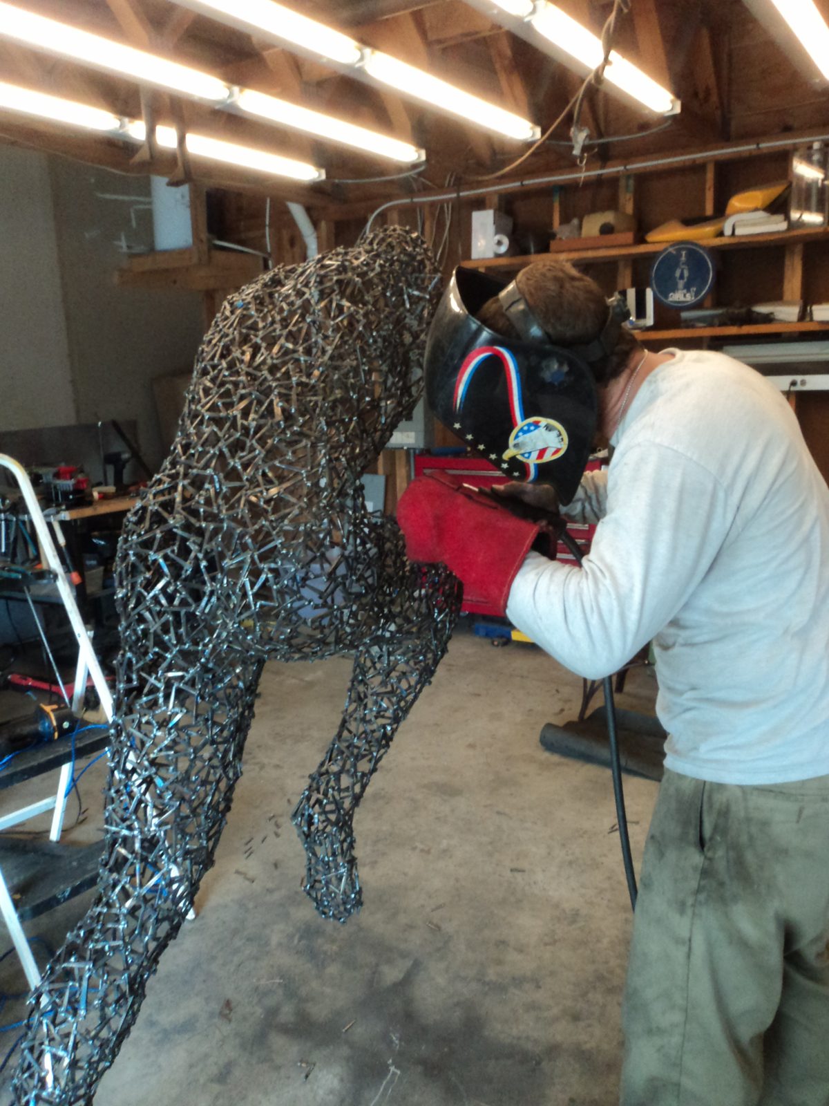 Corey Ellis welding Bella, a life-size masonry-nail figurative sculpture, in the studio
